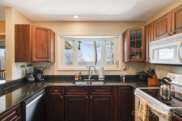a kitchen with granite countertop a sink stove and cabinets