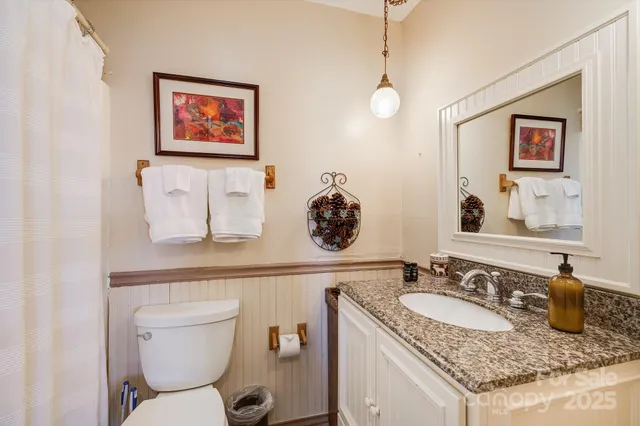 a bathroom with a granite countertop sink a toilet and mirror