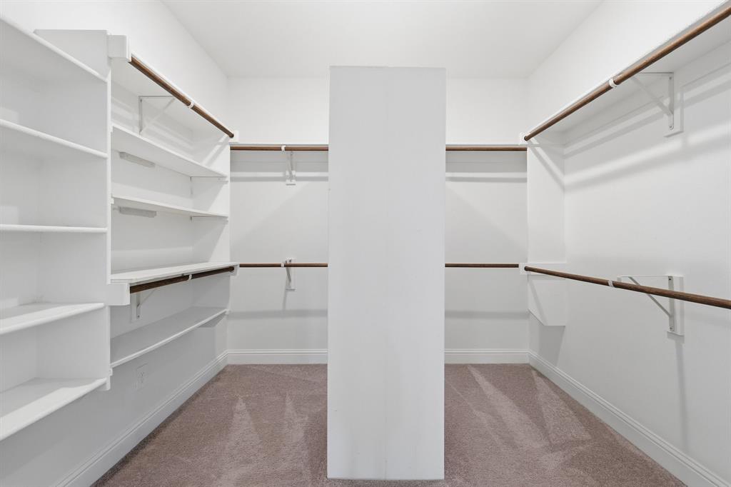 539 Farrell Lane Allen, TX 75013 - Photo 30 of 39 Walk-in closet featuring extensive built-in shelving, multiple hanging rods, white walls, white trim, and neutral-toned carpeting