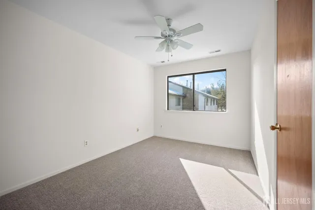 an empty room with a window and a chandelier fan