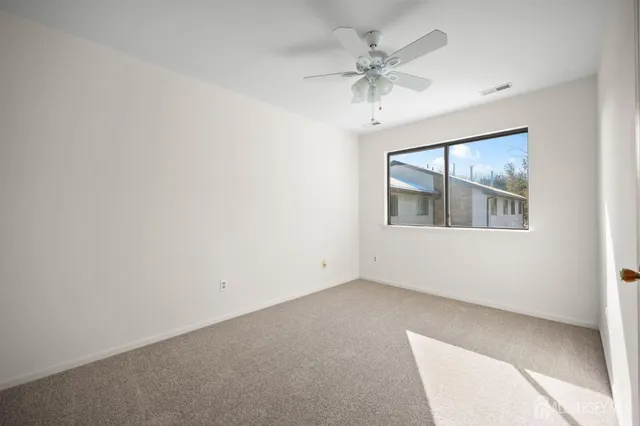 an empty room with a window and a fan