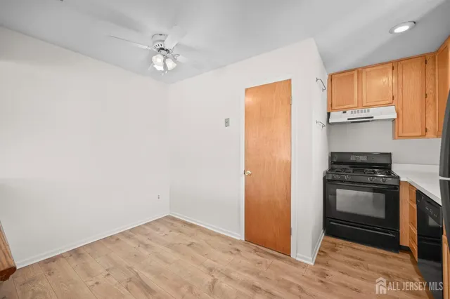 a kitchen with granite countertop a stove a sink and a refrigerator with wooden floor
