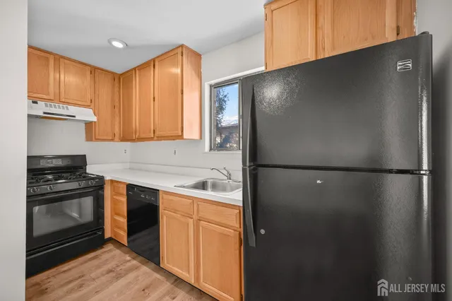 a kitchen with stainless steel appliances granite countertop a refrigerator a sink a stove and wooden cabinets