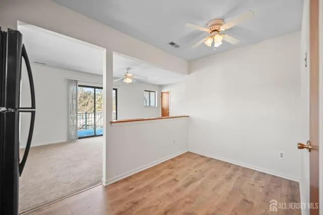 an empty room with chandelier fan and windows