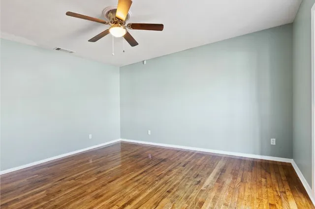 an empty room with wooden floor and a ceiling fan