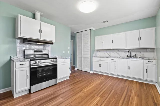 a kitchen with stainless steel appliances white cabinets and a wooden floors