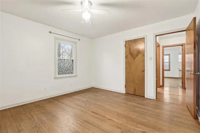 an empty room with wooden floor closet and windows