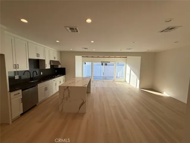 a view of a kitchen with kitchen island a sink wooden floor and a refrigerator