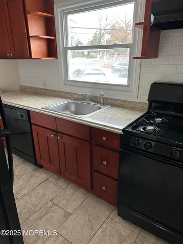 a kitchen with a sink a stove and wooden cabinets