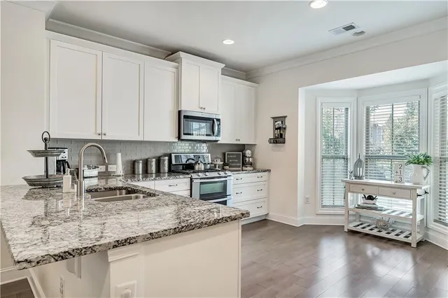 a kitchen with granite countertop white cabinets sink and stainless steel appliances