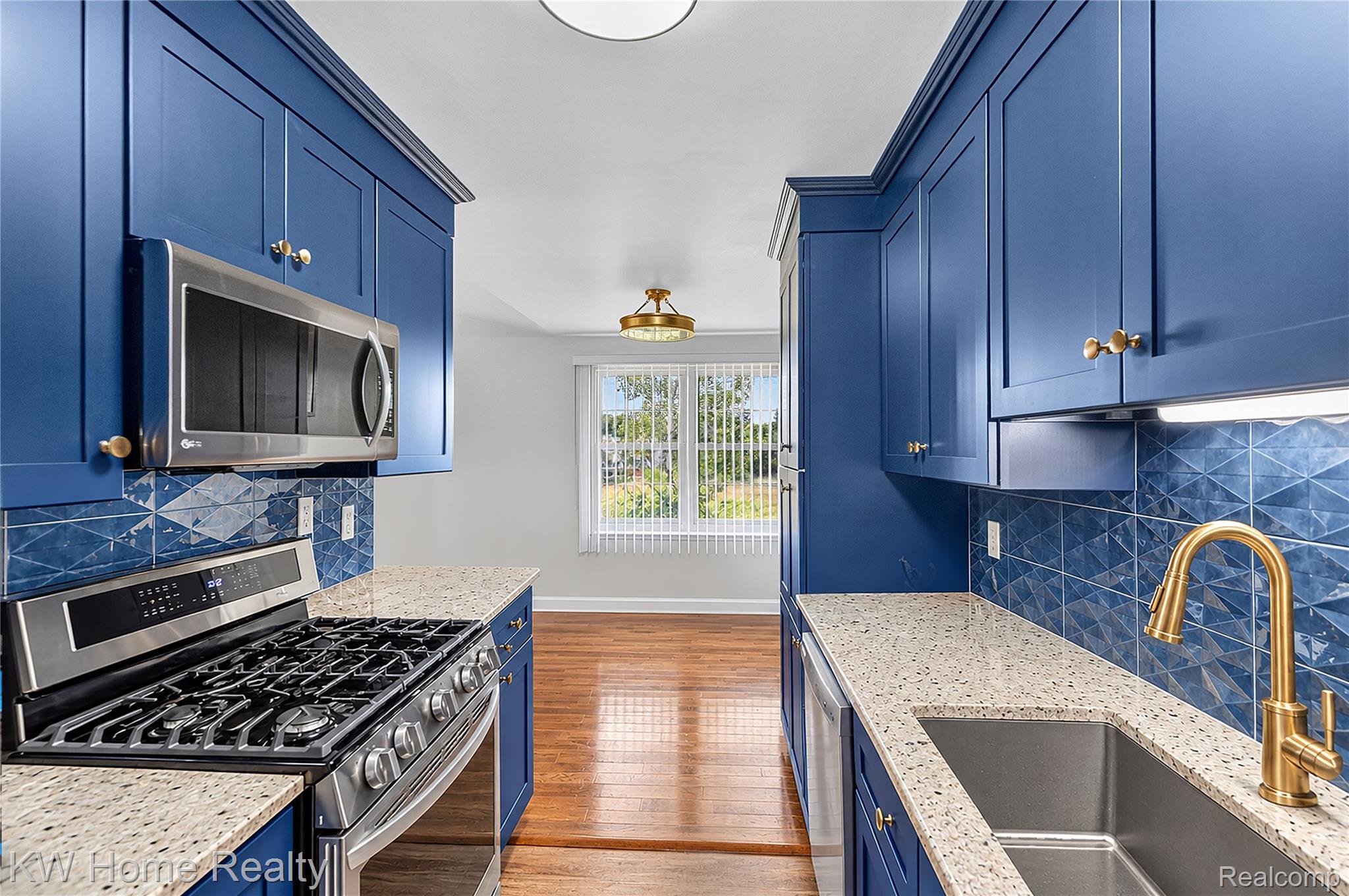 3216 High Pointe Ridge Road Lake Orion, MI 48359 - Photo 7 of 24 A new modern Kitchen featuring snazzy blue cabinetry, quartz countertops, stainless steel appliances, a decorative tile backsplash, and LVP flooring