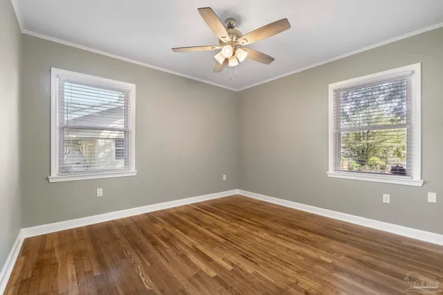 a view of an empty room with window and wooden floor