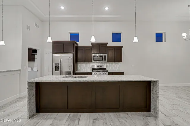 a kitchen with stainless steel appliances a sink a stove a microwave a refrigerator cabinets and wooden floor