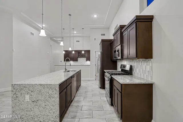 a kitchen with stainless steel appliances granite countertop a sink a stove top oven a counter space and cabinets