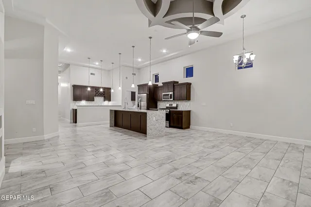 a large white kitchen with kitchen island stainless steel appliances cabinets a sink and a chandelier