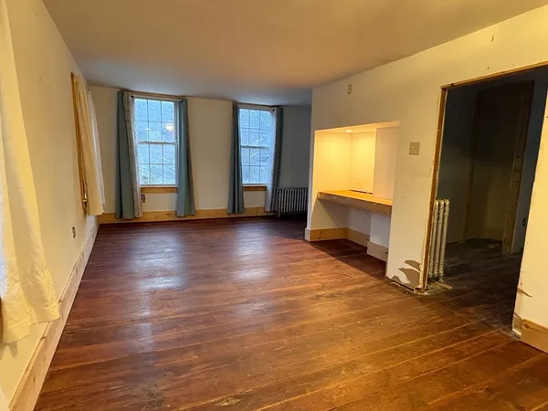 a view of an empty room with glass door and wooden floor