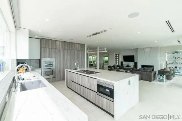 a view of a kitchen with kitchen island a stove a sink a refrigerator cabinets and wooden floor