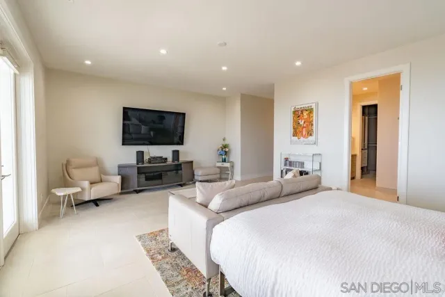 a bedroom with a bed a couch and a flat screen tv