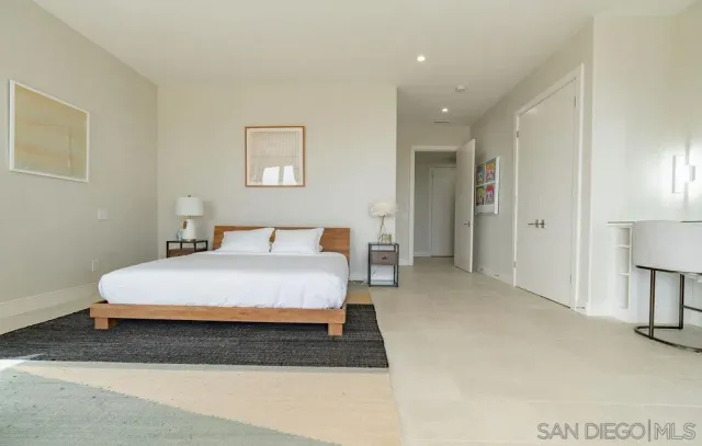 a spacious bedroom with a bed and a lamp