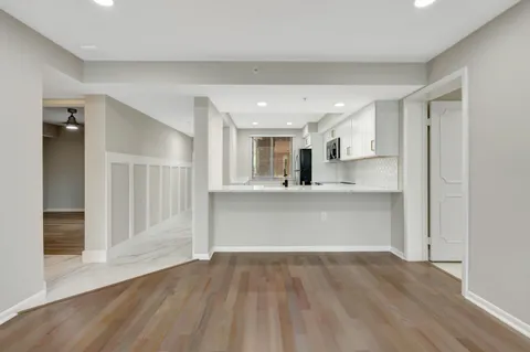 an empty room with wooden floor and a kitchen