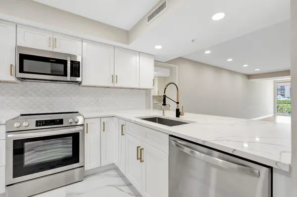 a kitchen with stainless steel appliances granite countertop a sink a stove a microwave and cabinets