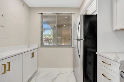 a view of a kitchen with white cabinets and a window
