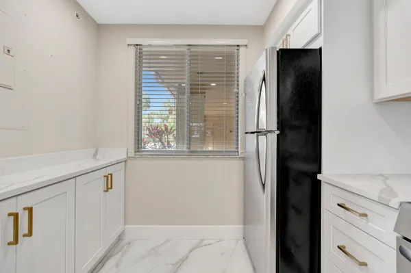 a view of a kitchen with white cabinets and a window