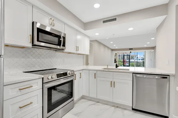 a kitchen with white cabinets stainless steel appliances and sink