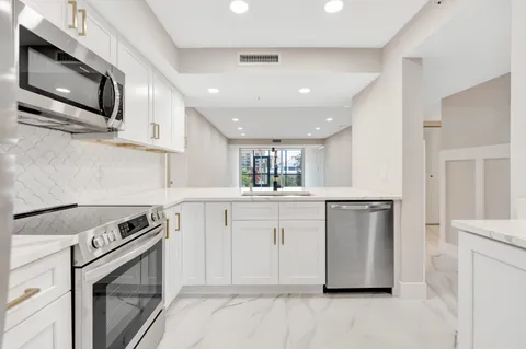 a kitchen with stainless steel appliances granite countertop a stove a sink and a microwave