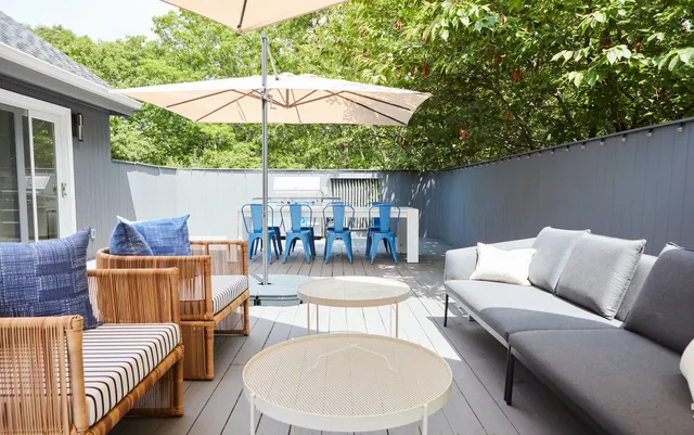 a view of a patio with couches chairs under an umbrella