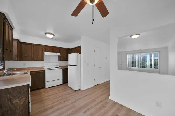 a kitchen with stainless steel appliances a stove a sink dishwasher and a refrigerator with wooden floor