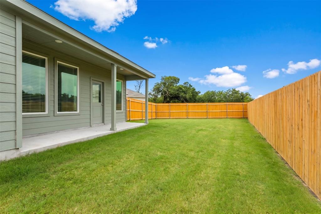 656 Waymaker Way Princeton, TX 75407 - Photo 40 of 40 Expansive backyard featuring a manicured lawn, a full wood privacy fence, and a covered patio with concrete flooring