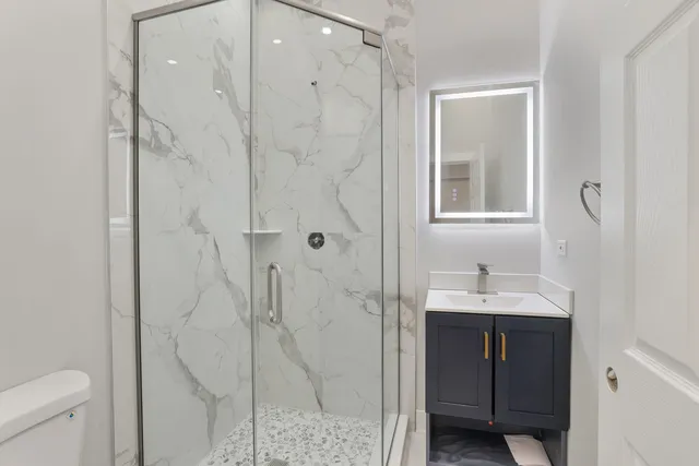 a bathroom with a shower sink vanity and toilet
