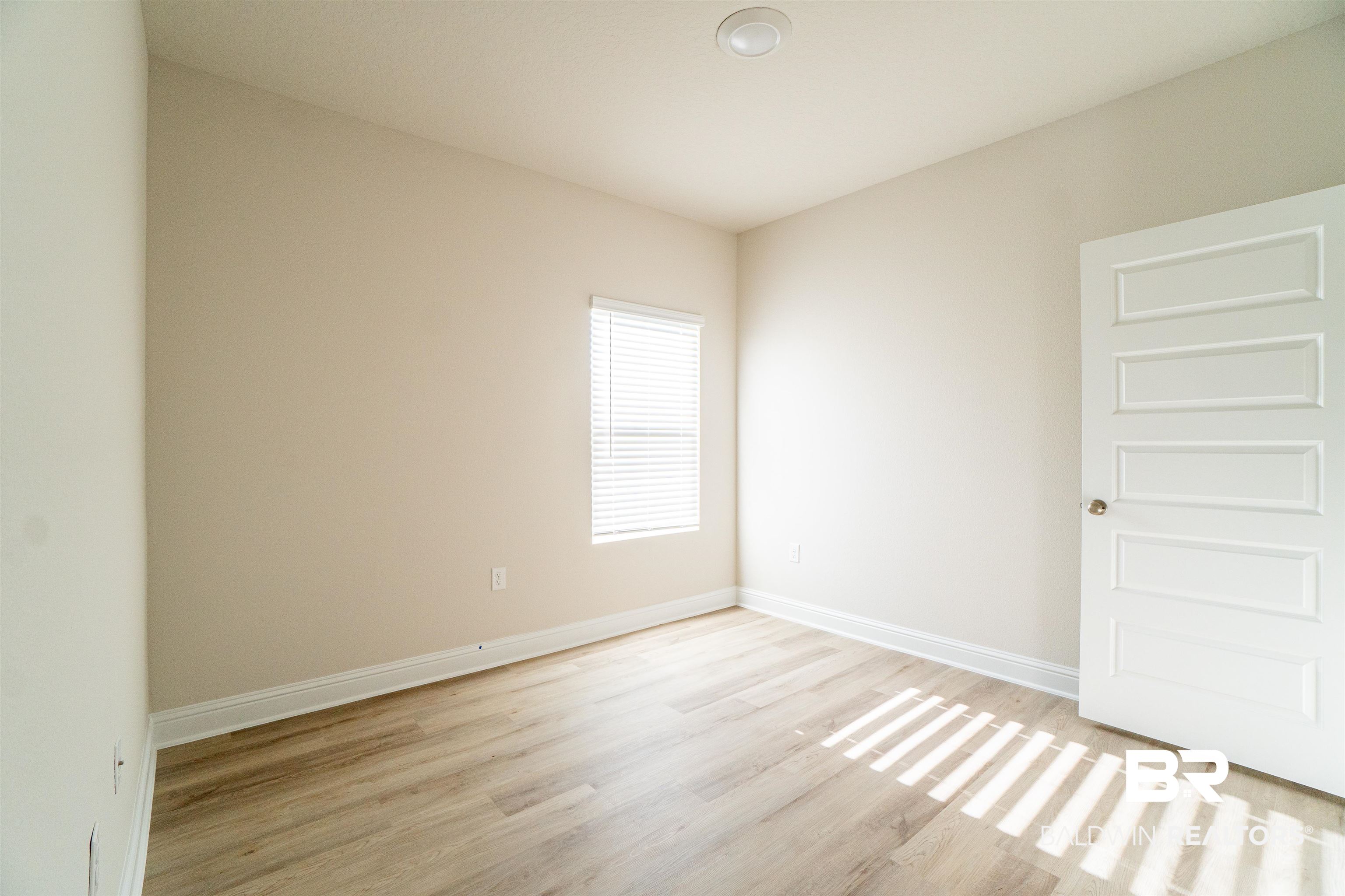 1073 Hayward Loop Foley, AL 36535 - Photo 7 of 18 Interior room featuring wood-finish flooring, light-toned walls, a single window with blinds, a ceiling-mounted light fixture, and a paneled door