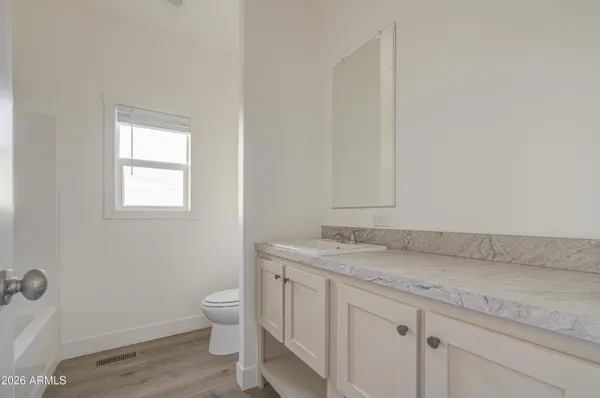 a bathroom with a granite countertop toilet a sink and a window