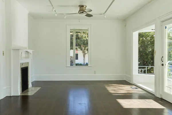 an empty room with wooden floor fan and windows