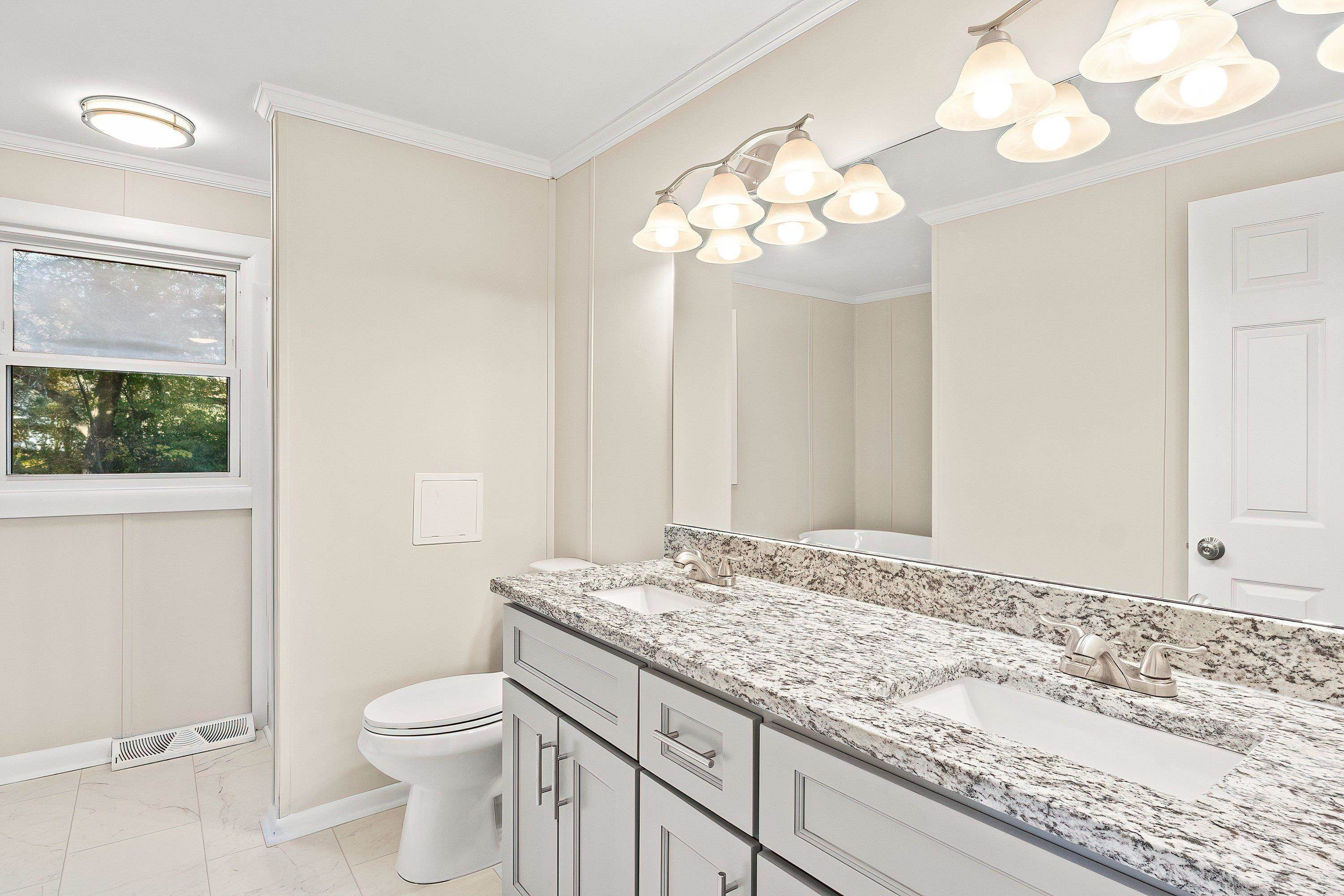 1313 Ewing Drive Garner, NC 27529 - Photo 30 of 46 a bathroom with a granite countertop sink a toilet and a mirror