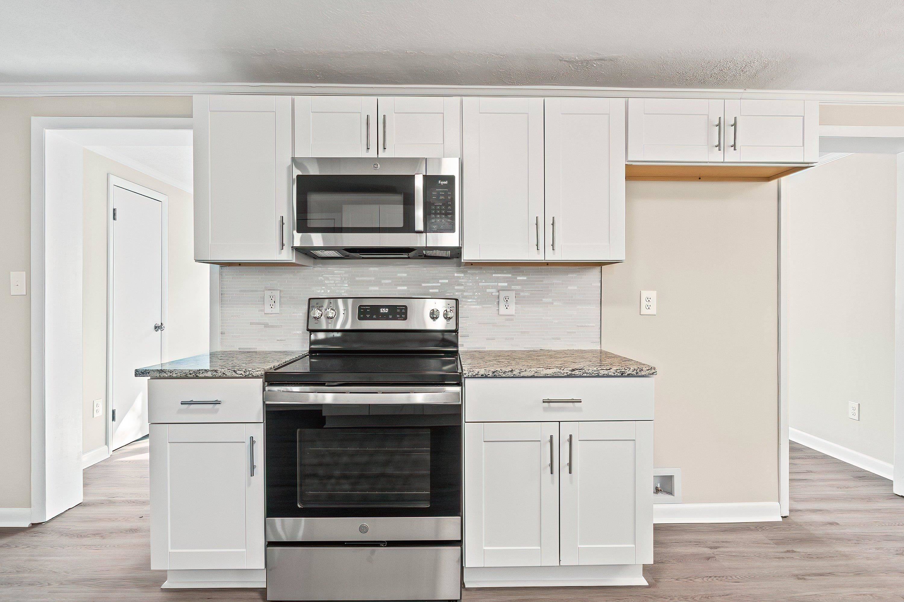 1313 Ewing Drive Garner, NC 27529 - Photo 7 of 46 a kitchen with cabinets stainless steel appliances and wooden floor