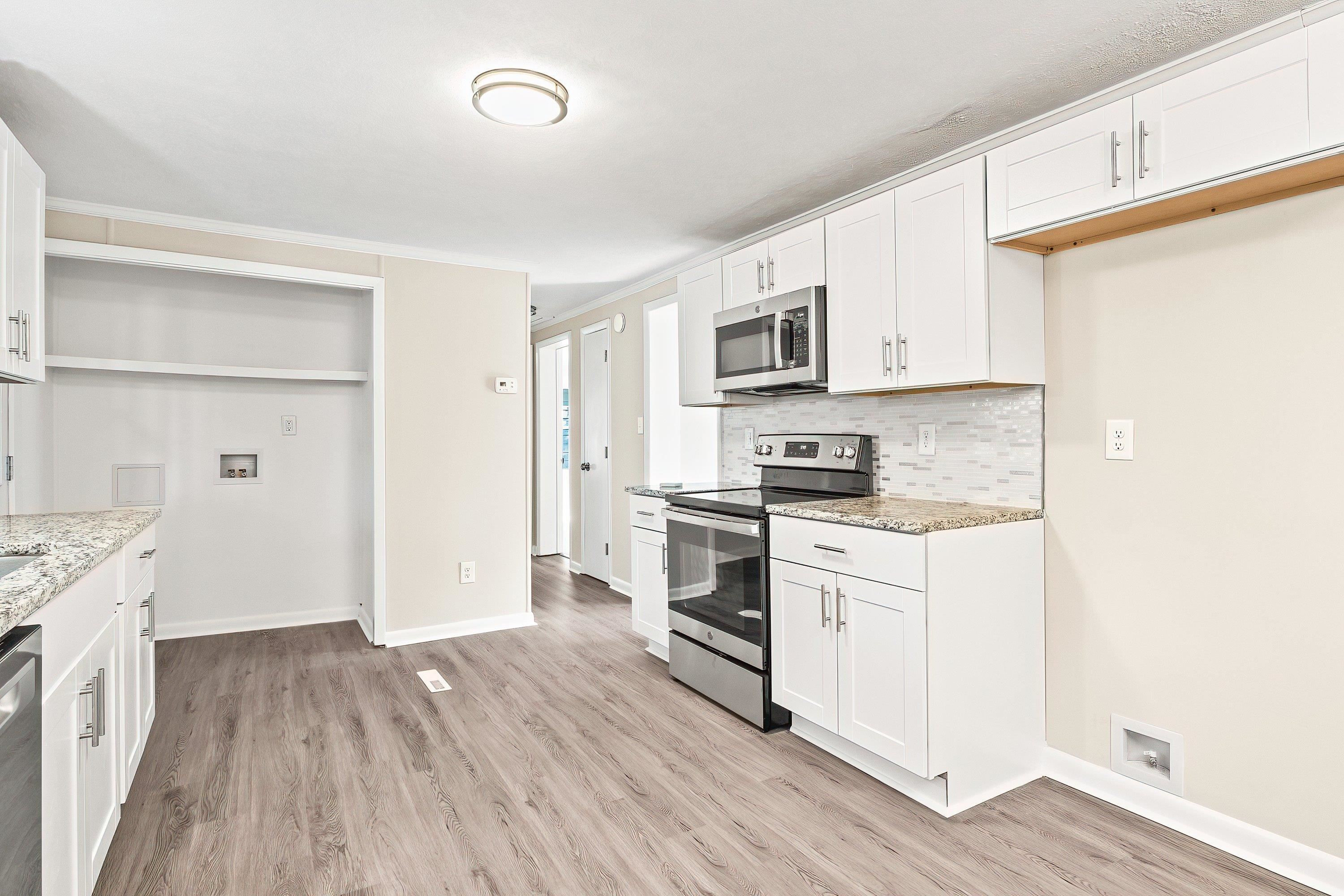 1313 Ewing Drive Garner, NC 27529 - Photo 10 of 46 a kitchen with granite countertop white cabinets and white appliances
