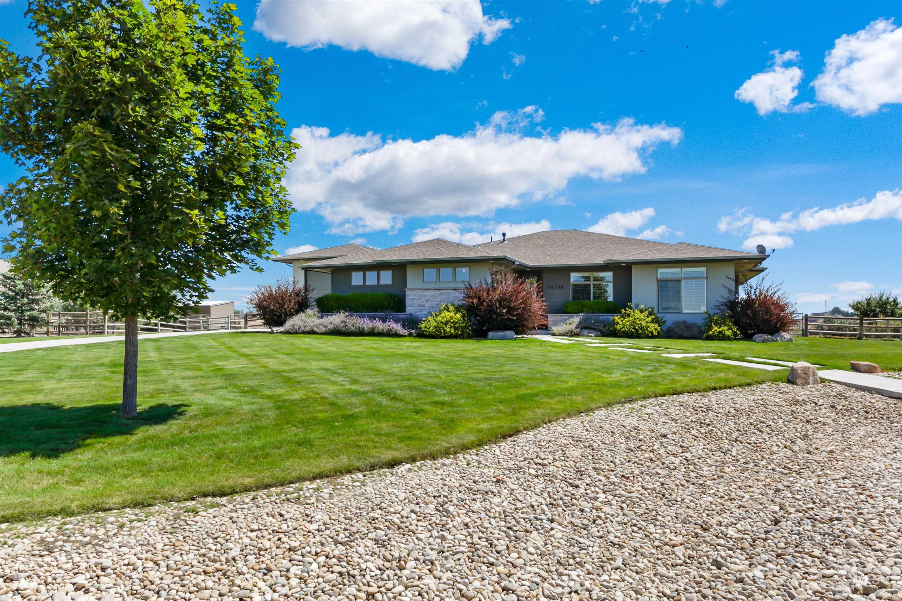 24398 Tombstone Ridge Court Middleton, ID 83644 - Photo 4 of 47 Contemporary ranch-style residence featuring a stucco exterior with stone accents, a gravel driveway, and a verdant lawn