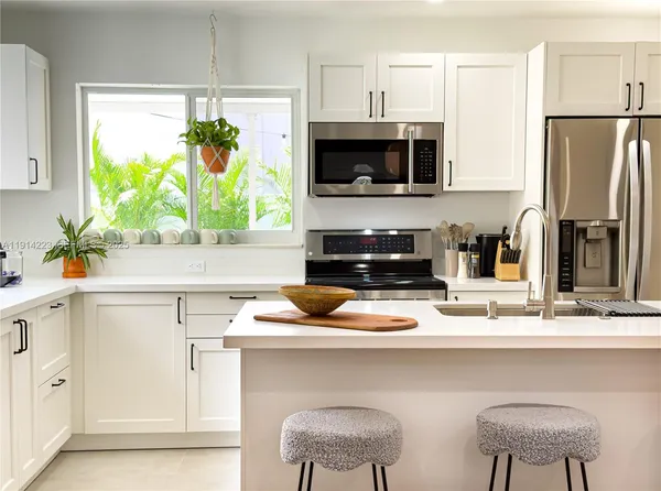 a kitchen with stainless steel appliances a white table and chairs in it