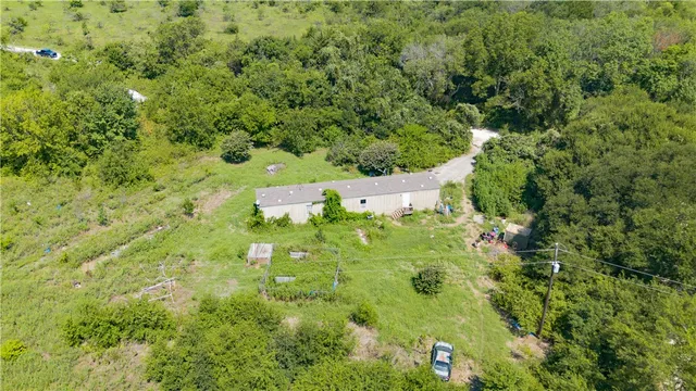 an aerial view of residential house with outdoor space and trees all around