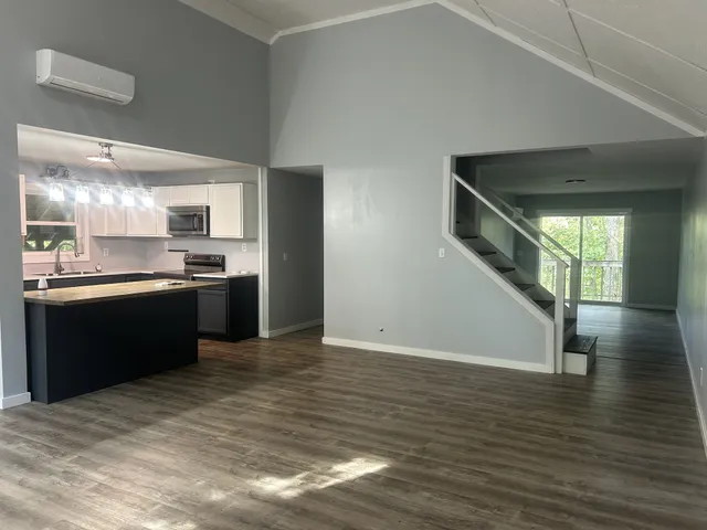 a kitchen with stainless steel appliances granite countertop a refrigerator a sink dishwasher a stove and white countertops with wooden floor