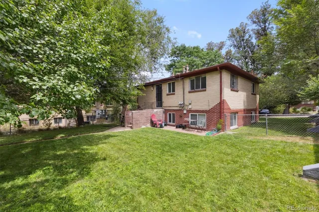 a view of a house with a big yard plants and large trees