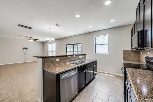 a kitchen with stainless steel appliances granite countertop a sink a stove and a refrigerator