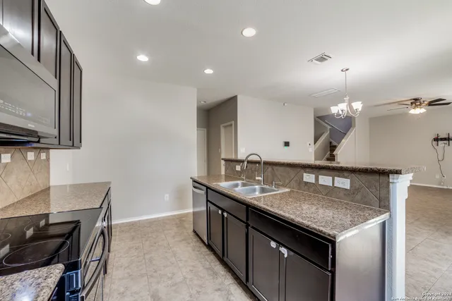 a kitchen with a stove kitchen island a sink and a refrigerator