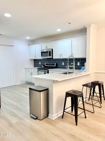 a kitchen with stainless steel appliances granite countertop a table chairs microwave and sink