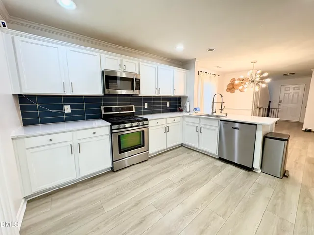 a kitchen with stainless steel appliances granite countertop a stove top oven a sink and white cabinets