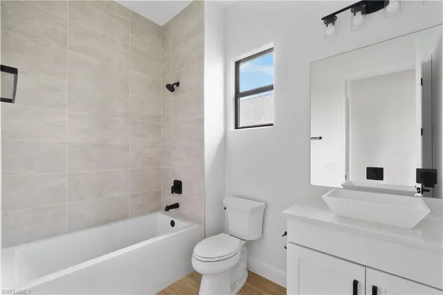 a bathroom with a bathtub shower sink vanity mirror and toilet
