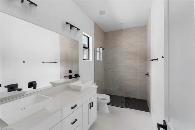a bathroom with a double vanity sink toilet and shower